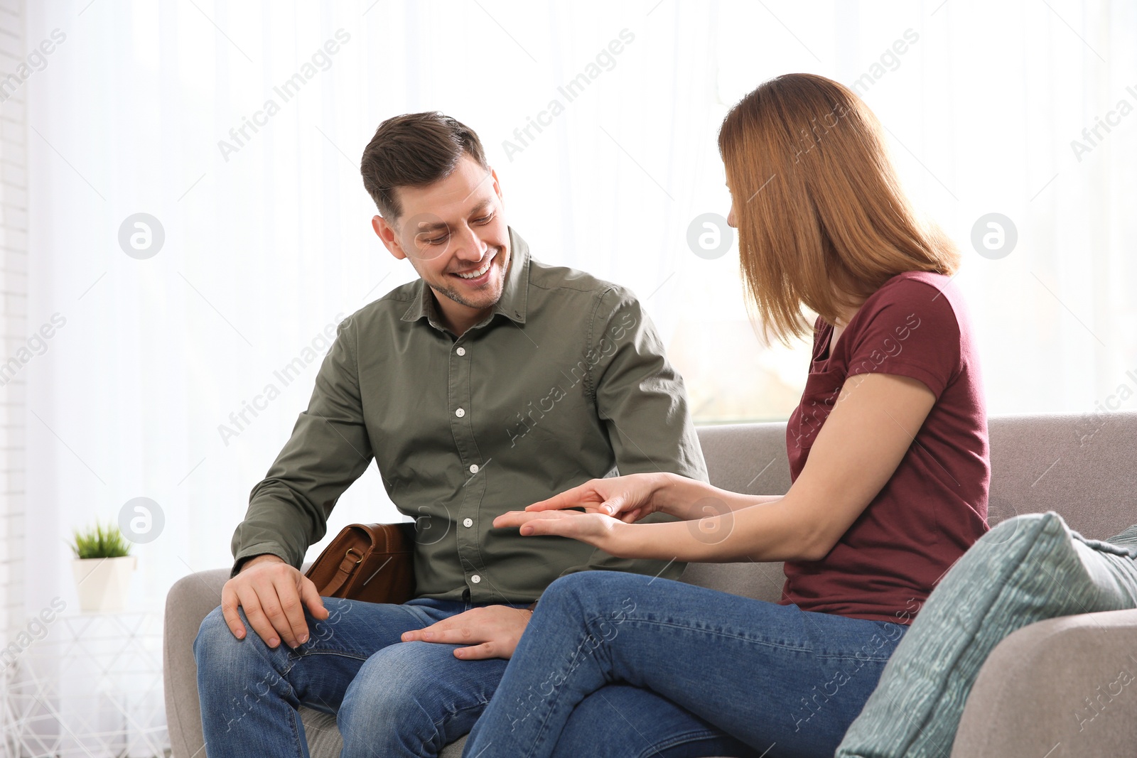 Photo of Hearing impaired friends using sign language for communication on sofa in living room