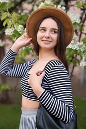 Beautiful woman in hat near blossoming tree on spring day