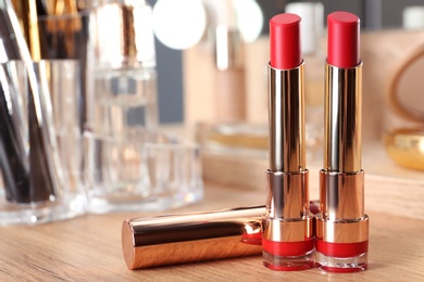 Open lipsticks in gold tubes on dressing table, space for text