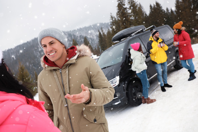 Group of friends near car on snowy road. Winter vacation