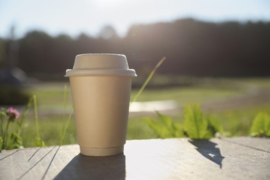 Photo of Cardboard takeaway coffee cup with lid on stone parapet outdoors, space for text