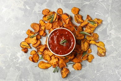 Photo of Sweet potato chips and bowl of sauce on grey background, top view