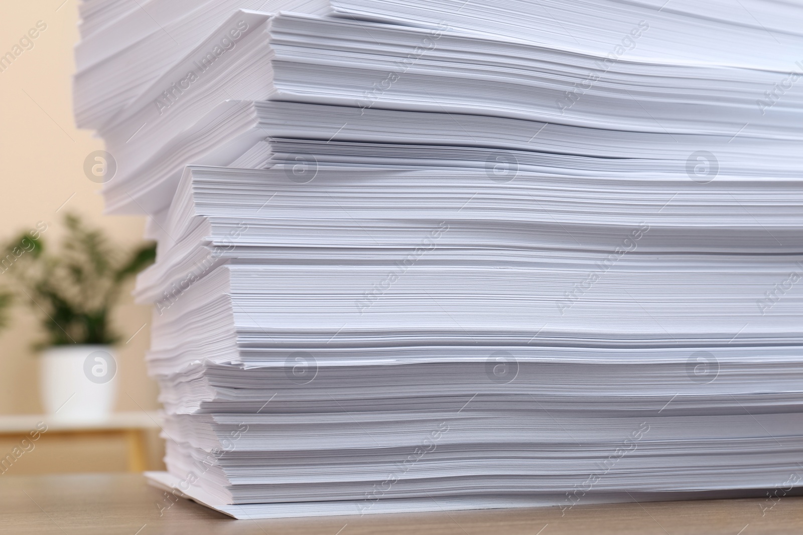 Photo of Stack of paper sheets on wooden table indoors, closeup