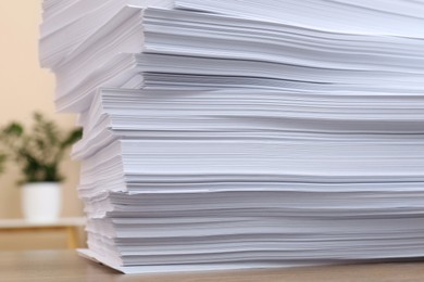 Photo of Stack of paper sheets on wooden table indoors, closeup