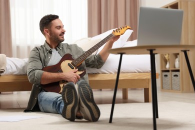 Photo of Music teacher with guitar conducting online lesson at home. Time for hobby