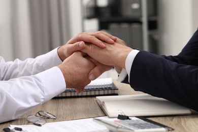 Photo of Trust and deal. Men joining hands in office, closeup