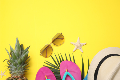 Beach accessories on yellow background, flat lay. Space for text