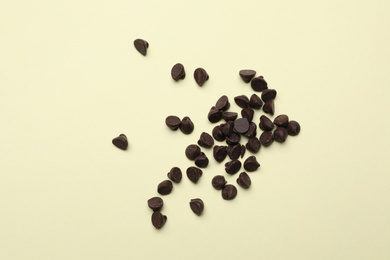 Pile of delicious chocolate chips on beige background, top view