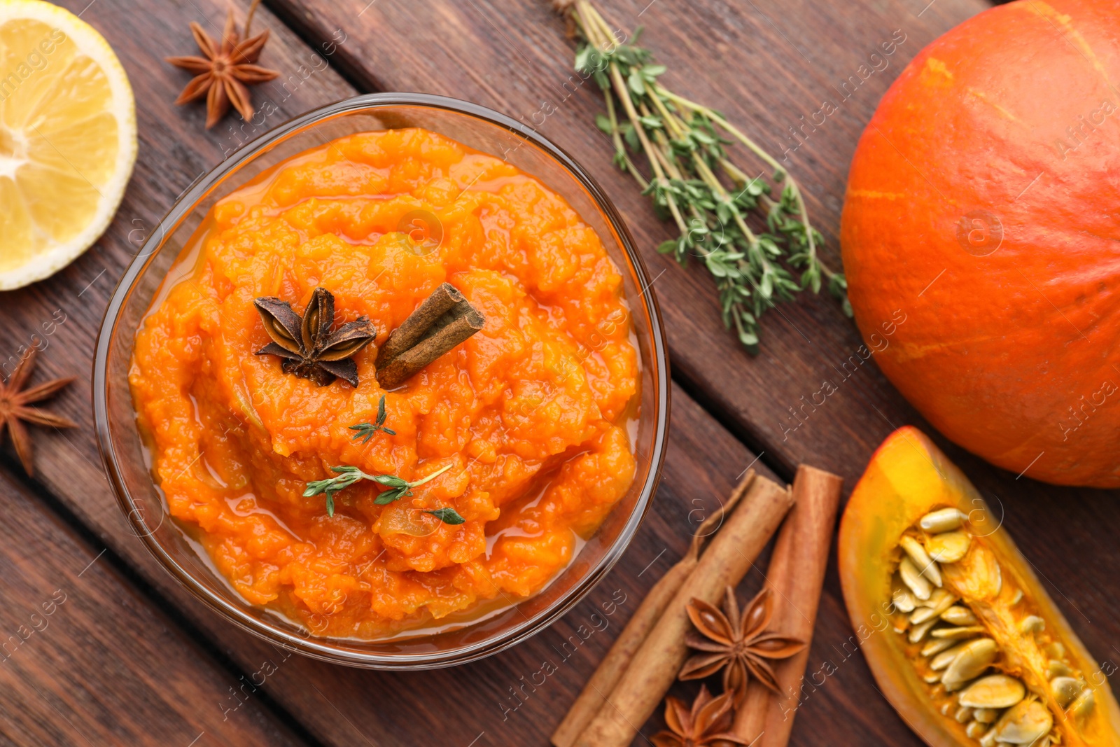 Photo of Bowl of delicious pumpkin jam and ingredients on wooden table, flat lay