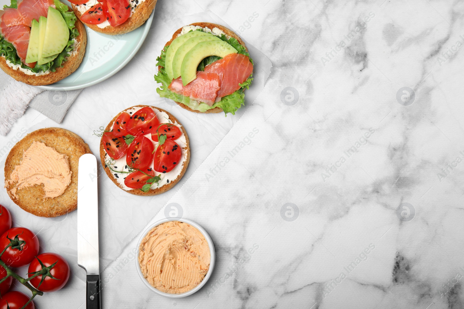 Photo of Tasty rusks with different toppings on white marble table, flat lay. Space for text