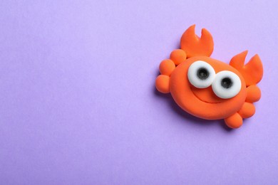 Colorful crab made from play dough on violet background, top view. Space for text