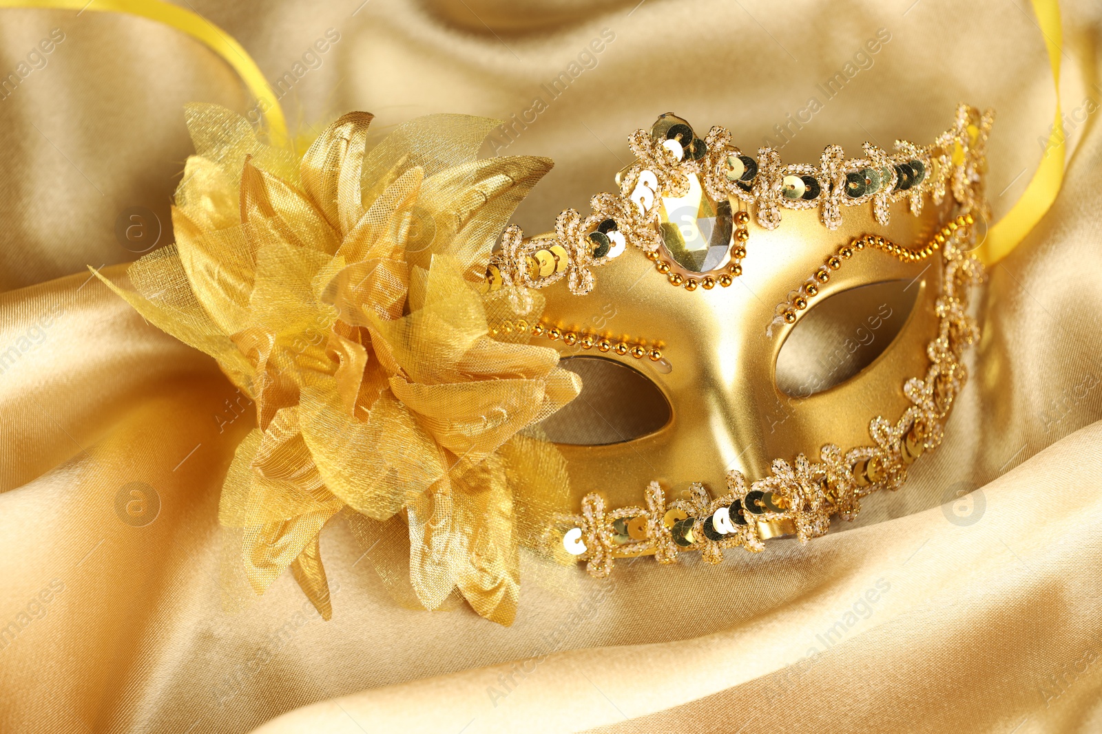 Photo of Beautifully decorated face mask on golden fabric. Theatrical performance