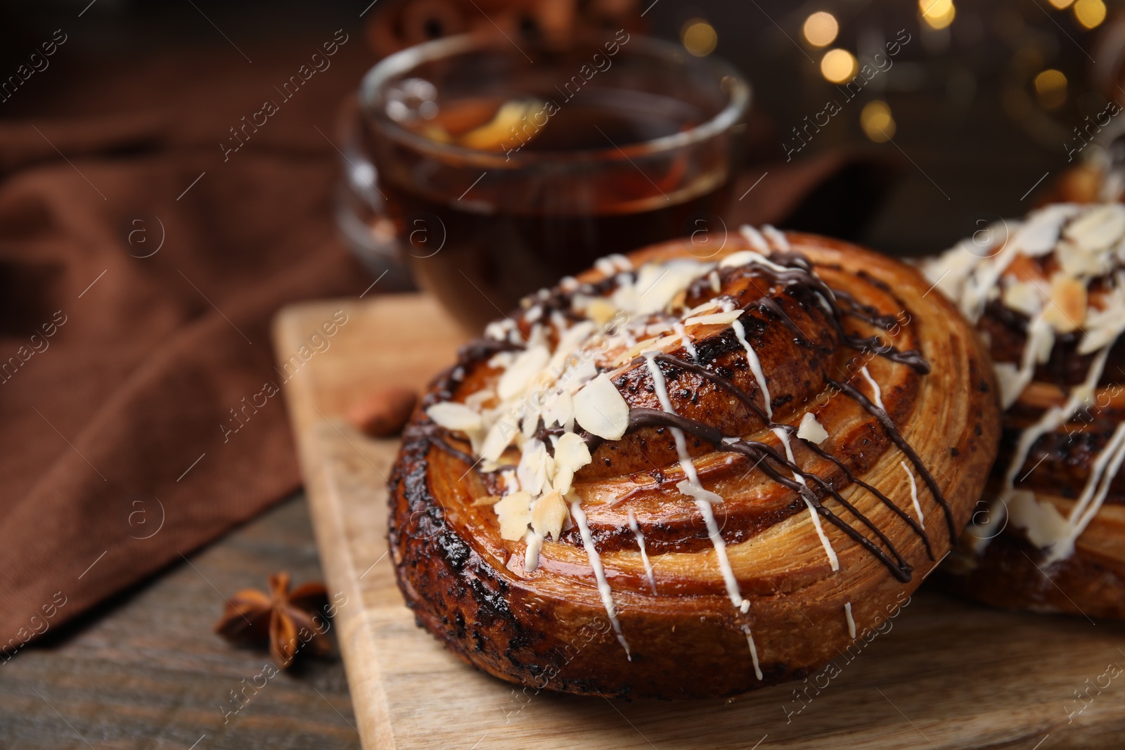 Photo of Sweet bun. Delicious roll with toppings and nuts on wooden table, closeup. Space for text