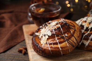 Photo of Sweet bun. Delicious roll with toppings and nuts on wooden table, closeup. Space for text