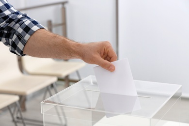 Photo of Man putting his vote into ballot box at polling station, closeup. Space for text
