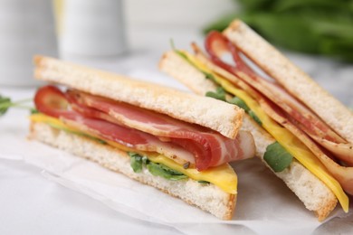 Photo of Delicious sandwiches with bacon on white table, closeup