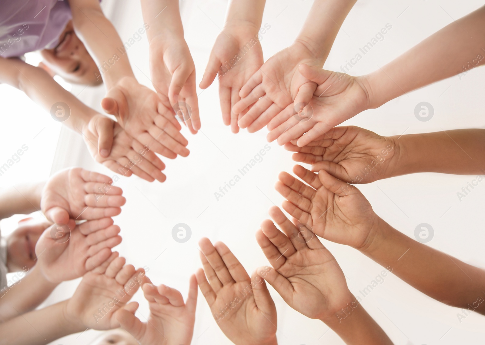 Photo of Little children putting their hands together indoors, view from below. Unity concept