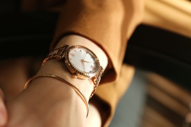 Woman wearing luxury wristwatch near mirror, closeup