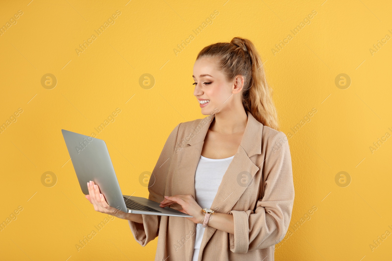 Photo of Portrait of beautiful young woman with laptop on yellow background