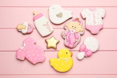 Photo of Set of baby shower cookies on pink wooden table, flat lay
