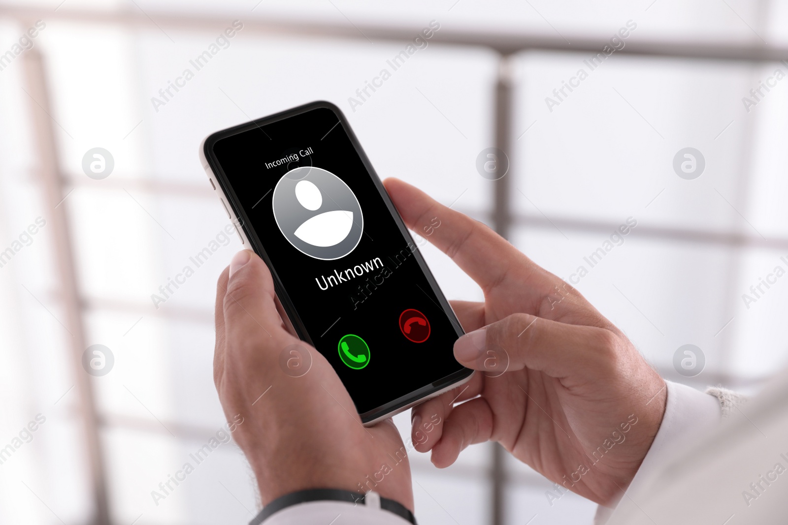 Image of Man deciding answer incoming call from unknown caller or not indoors, closeup. Be careful - fraud