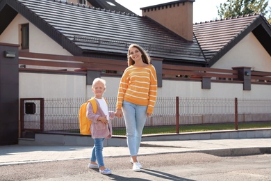 Young mother taking her little child to school on street