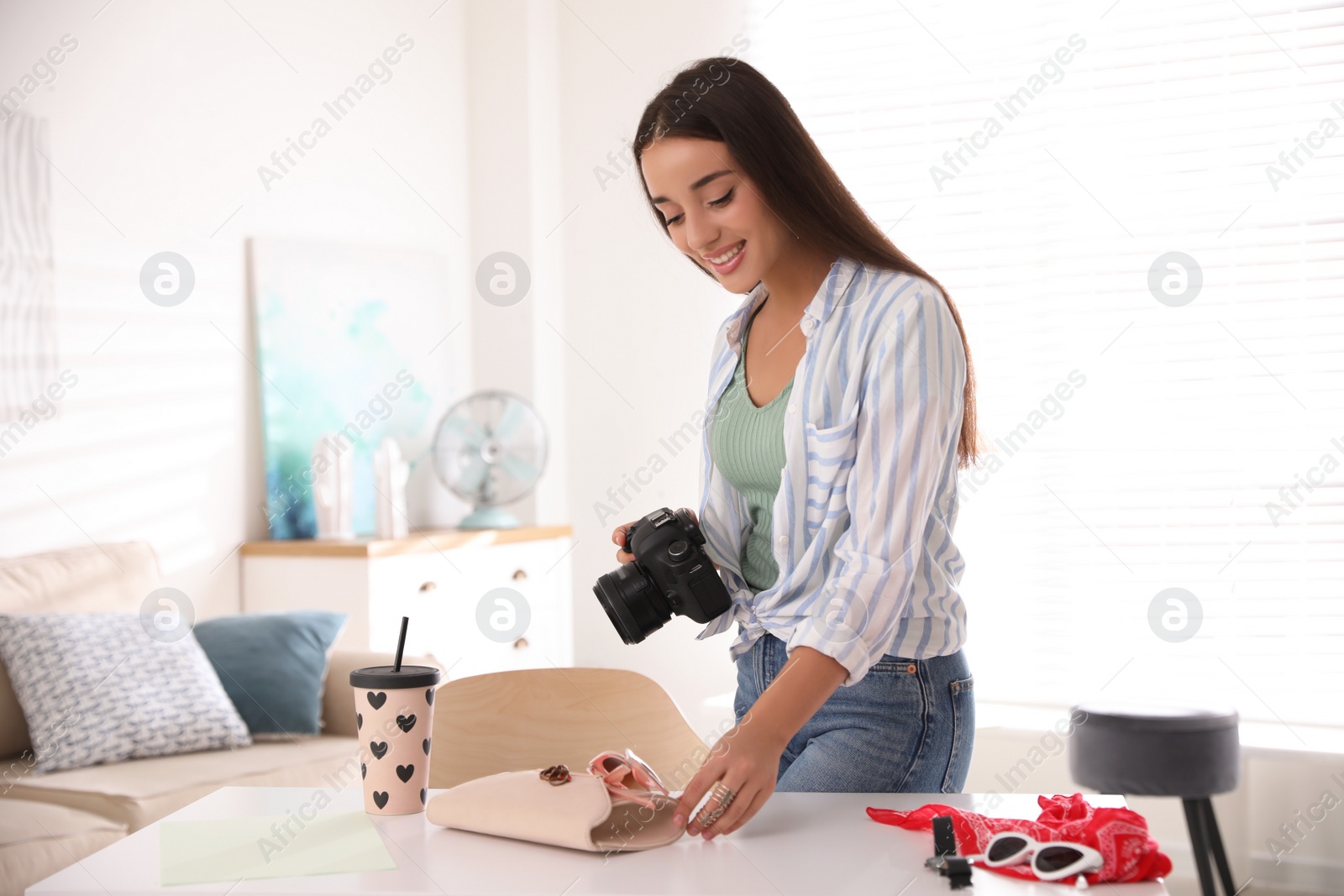 Photo of Young photographer taking picture of accessories indoors
