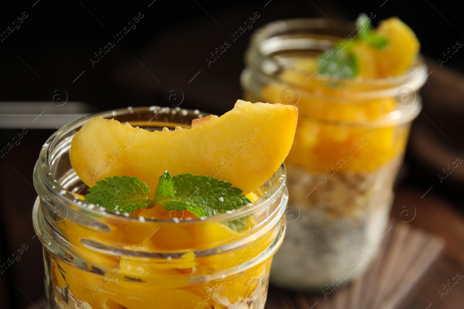 Photo of Tasty peach dessert with yogurt and granola on table, closeup