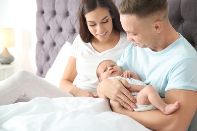 Happy couple with their newborn baby on bed