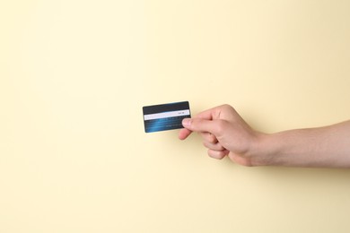 Photo of Man holding credit card on pale yellow background, closeup