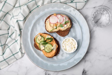Photo of Delicious sandwiches with hummus and different ingredients on white marble table, flat lay