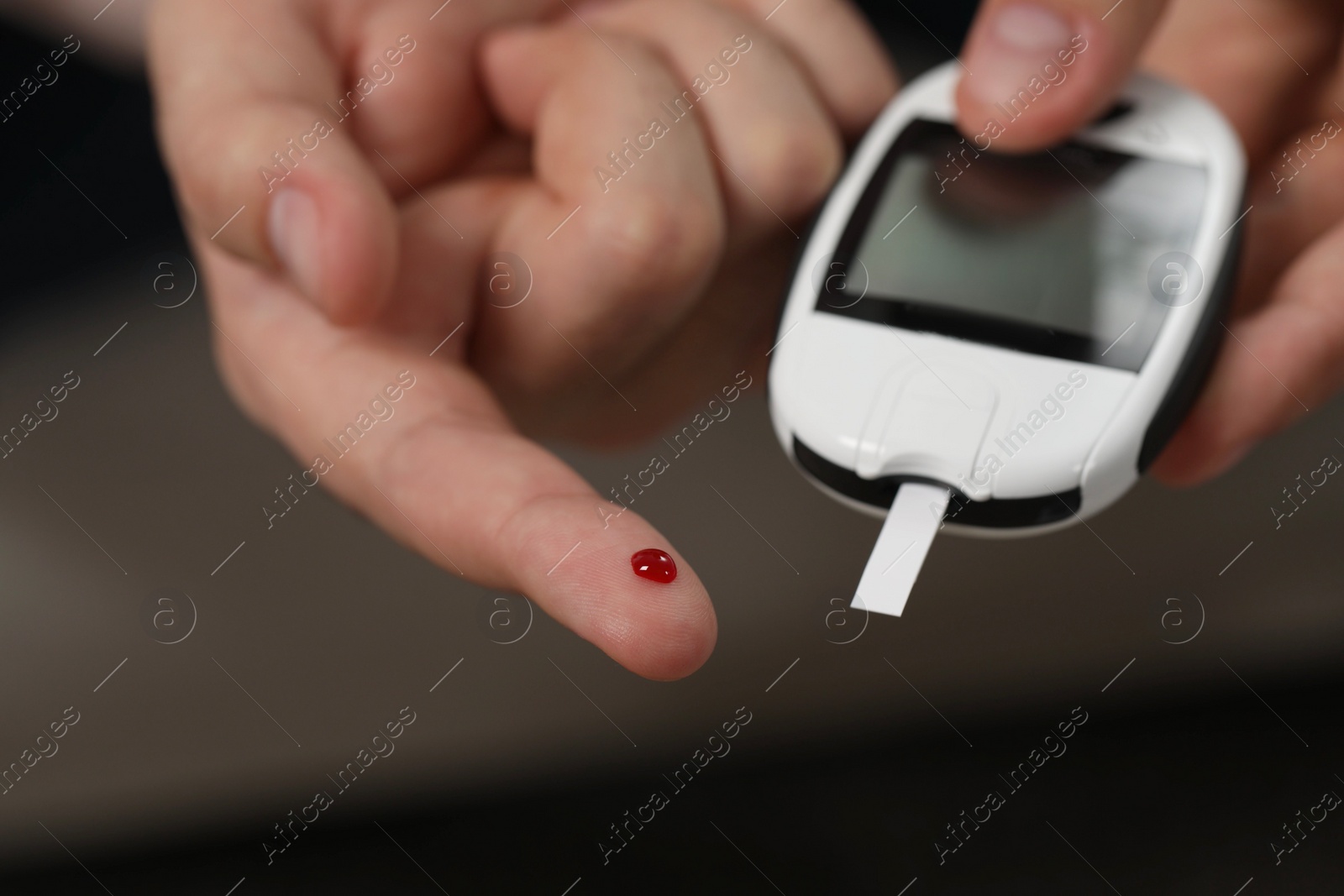 Photo of Diabetes test. Man checking blood sugar level with glucometer on blurred background, closeup