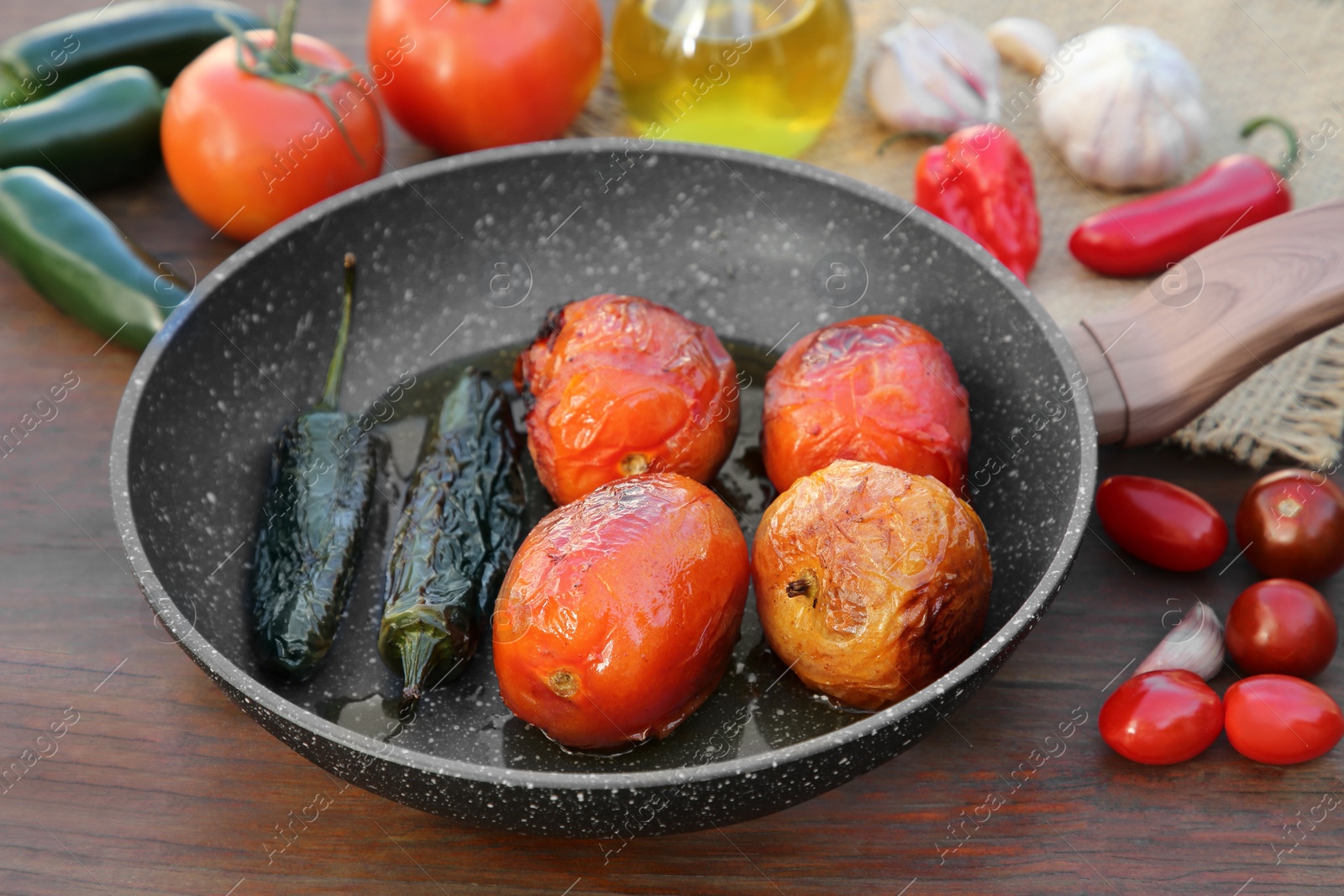 Photo of Frying pan and ingredients for salsa sauce on wooden table