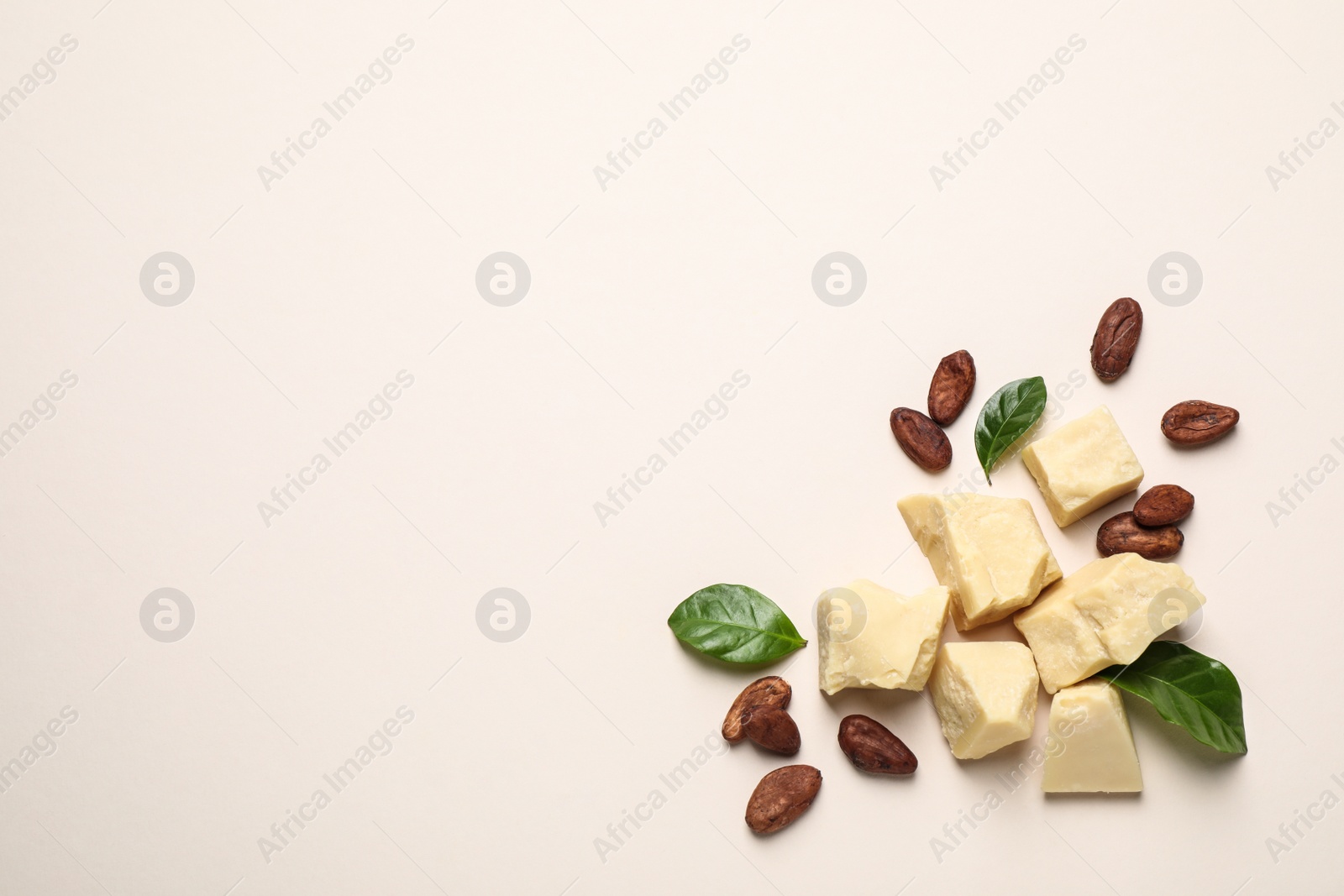 Photo of Organic cocoa butter and beans on beige background, flat lay. Space for text