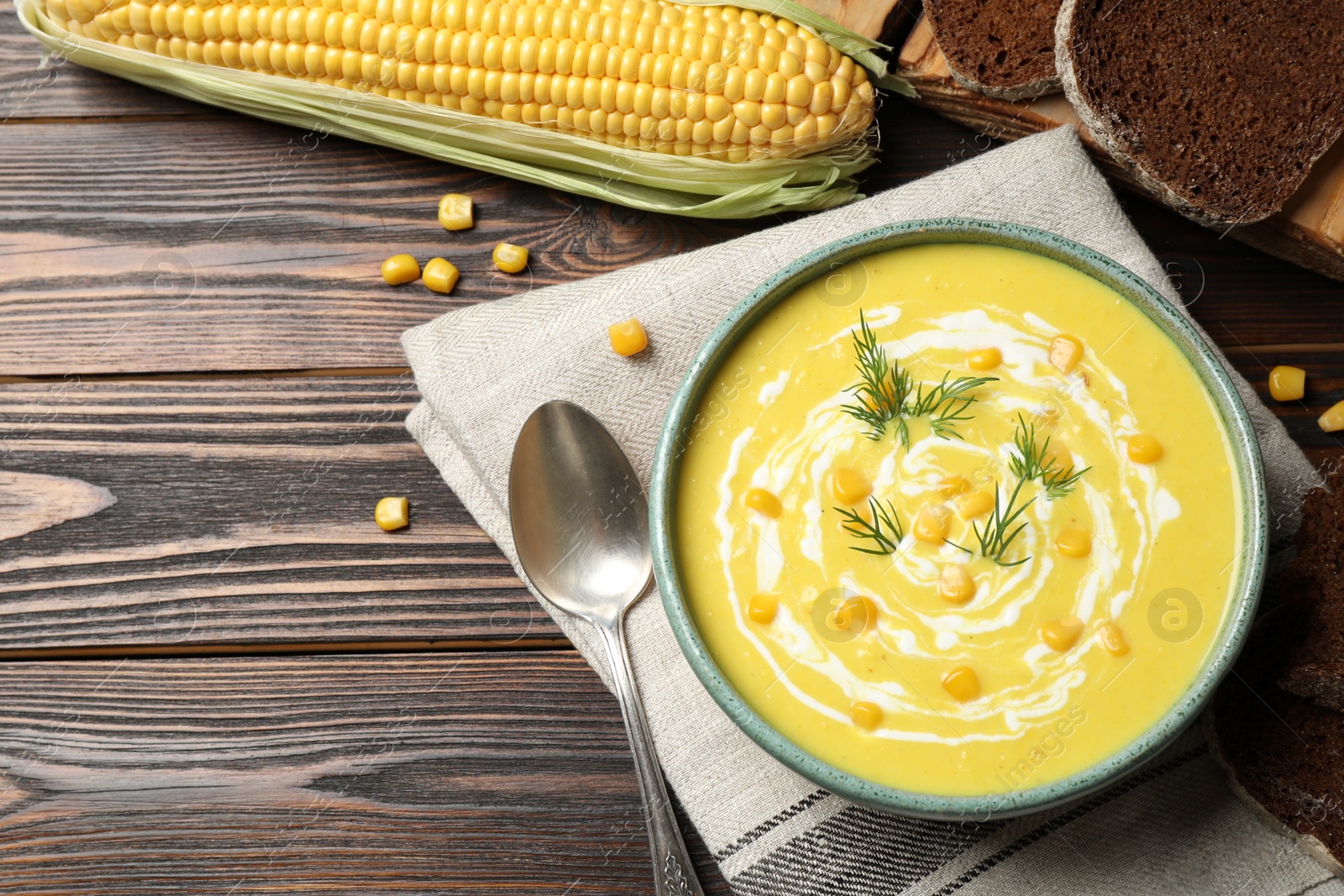 Photo of Delicious creamy corn soup served on wooden table, flat lay