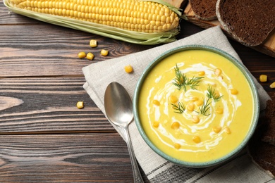 Delicious creamy corn soup served on wooden table, flat lay