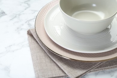 Photo of Clean plates, bowl and napkin on white table, closeup. Space for text