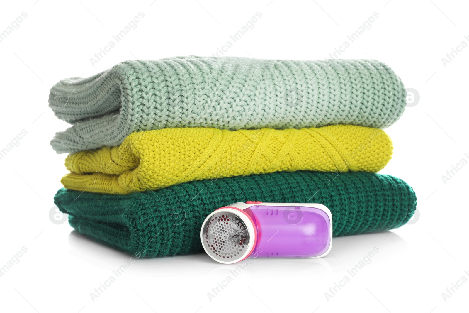 Photo of Modern fabric shaver and woolen clothes on white background