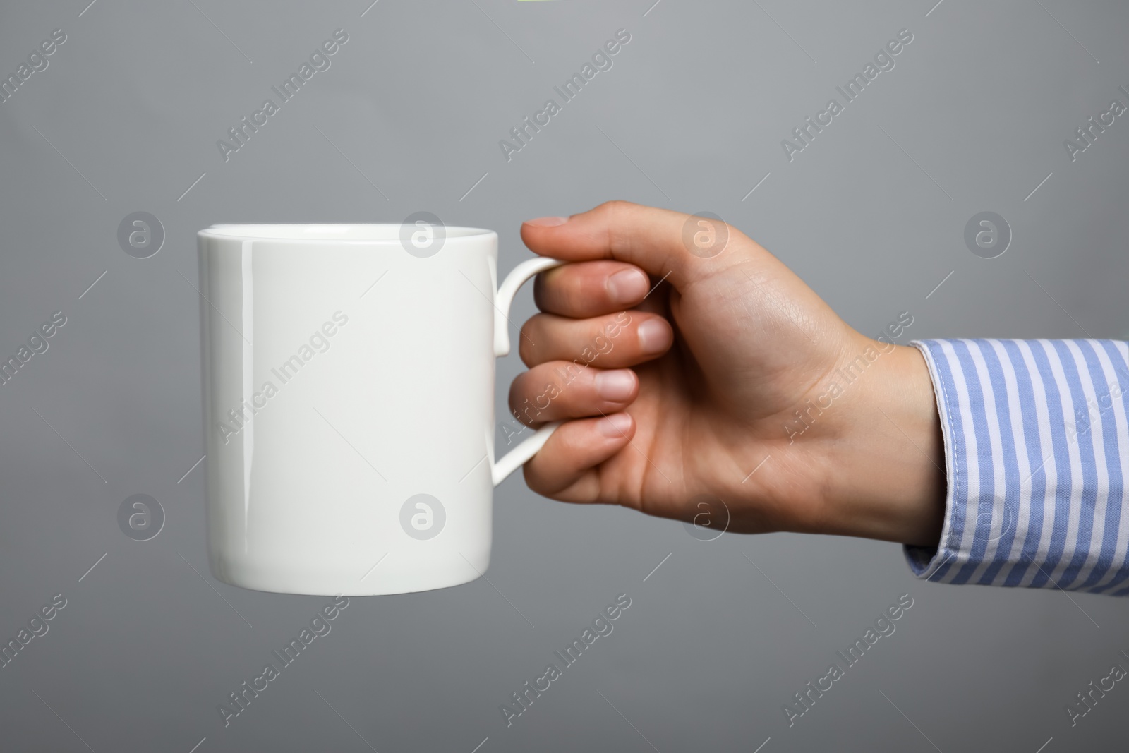 Photo of Woman holding white mug on light grey background, closeup