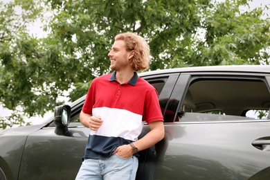 Photo of Attractive young man near luxury car outdoors