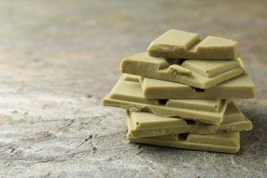Photo of Stacked pieces of tasty matcha chocolate on textured table, closeup. Space for text