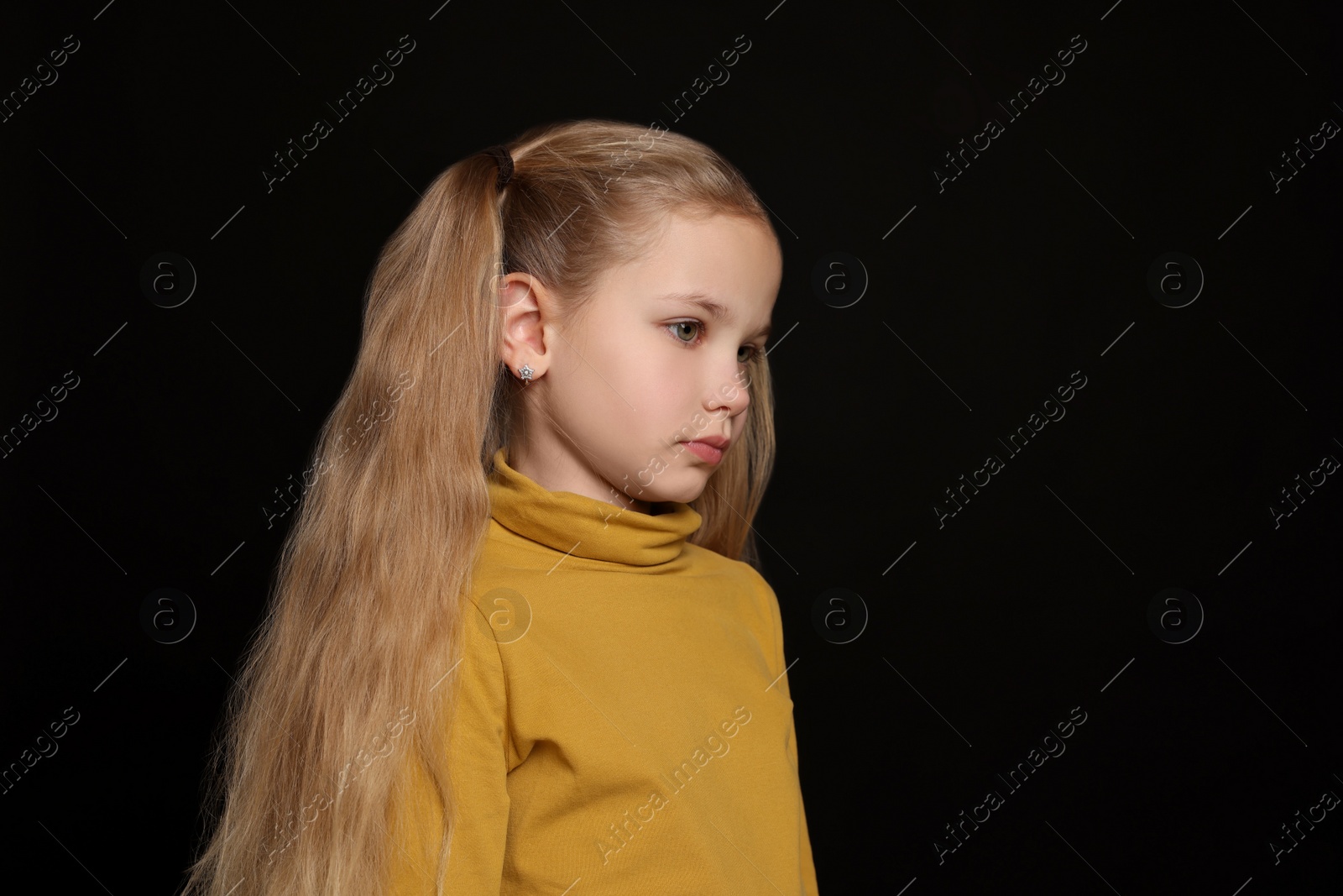 Photo of Little girl on black background, space for text. Children's bullying
