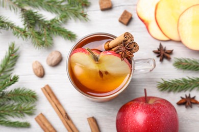 Photo of Hot mulled cider, ingredients and fir branches on white wooden table, flat lay