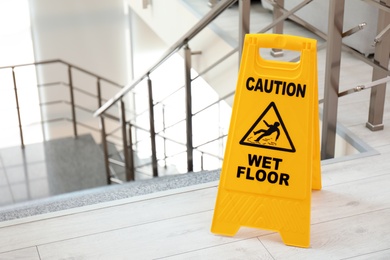 Photo of Safety sign with phrase Caution wet floor near stairs. Cleaning service