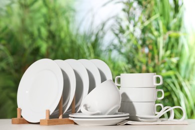 Set of clean dishware on white table against blurred background