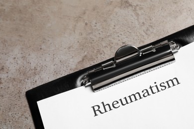 Photo of Clipboard with word Rheumatism on light gray textured background, closeup