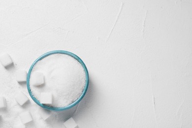 Different types of sugar in bowl on white table, flat lay. Space for text