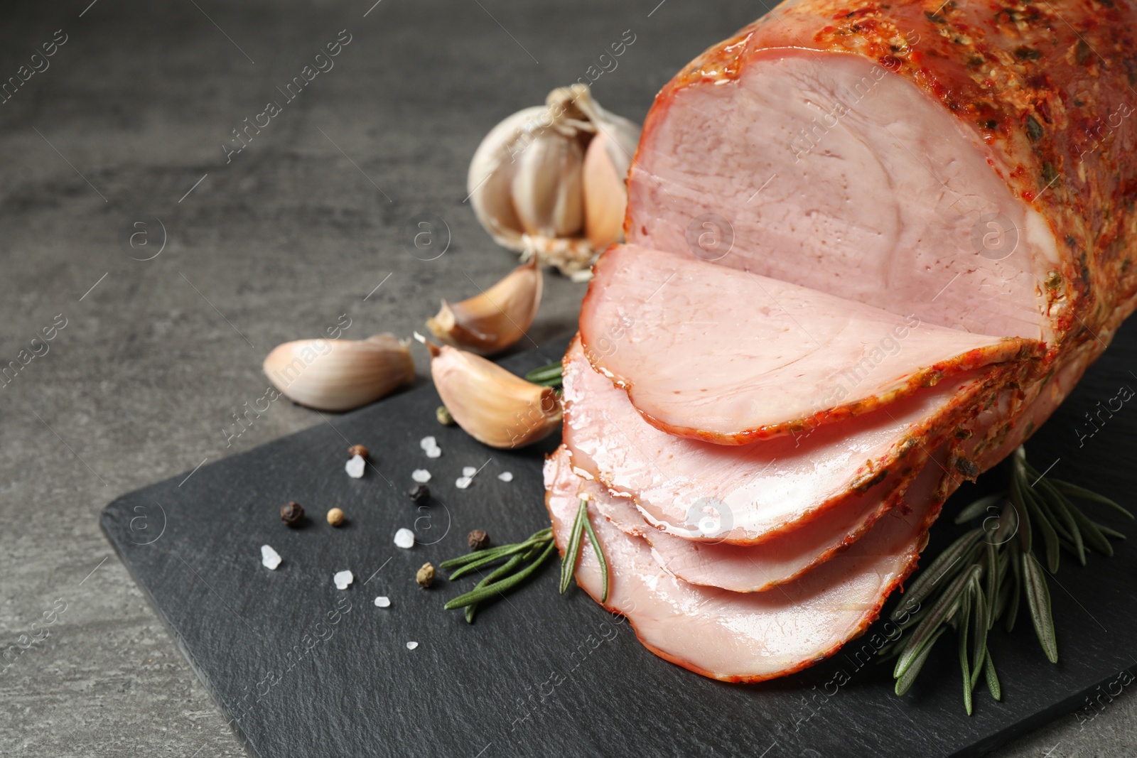Photo of Slate plate with delicious ham on grey table, closeup. Space for text