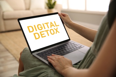 Woman using laptop with text Digital Detox at home, closeup