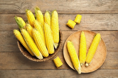 Tasty sweet corn cobs on wooden table, flat lay